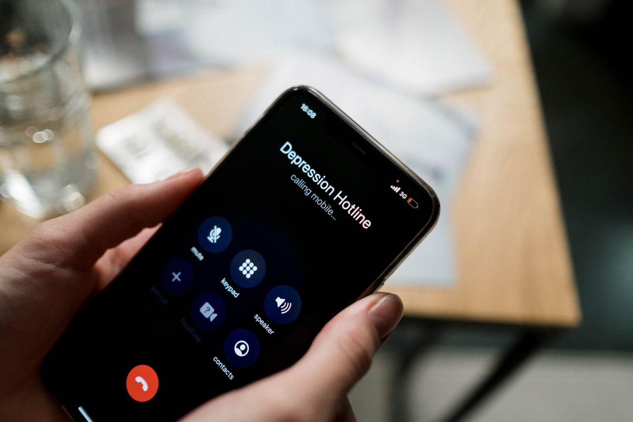 Close-up of a person holding a smartphone, calling a depression hotline.